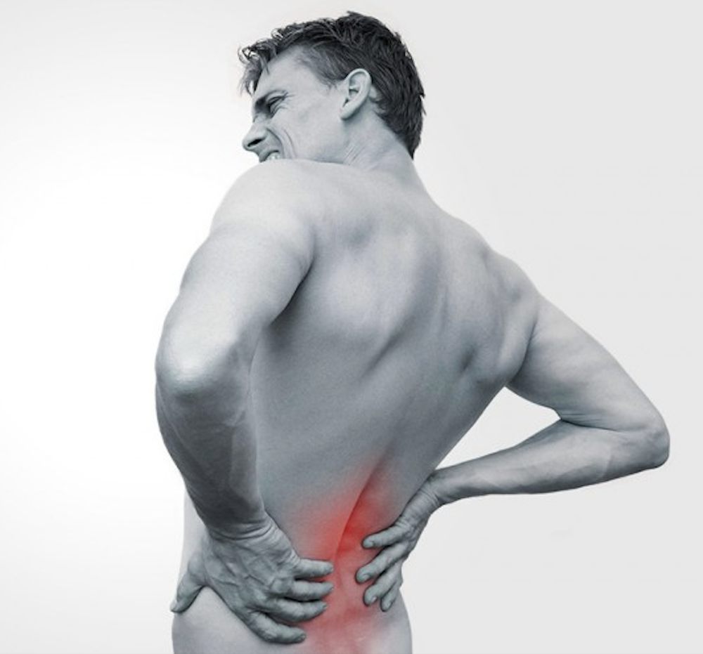 A man holding his lower back in pain, the painful area highlighted in red